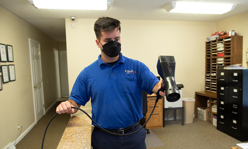 Tech using disinfectant sprayer in commercial office