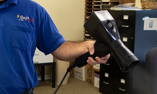 Tech using disinfectant sprayer in commercial office