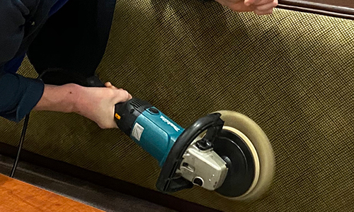 Tech using cleaning tool on booth in commercial restaurant