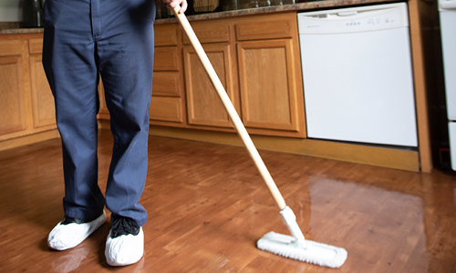 Using mop to clean hardwood flooring in a residential kitchen
