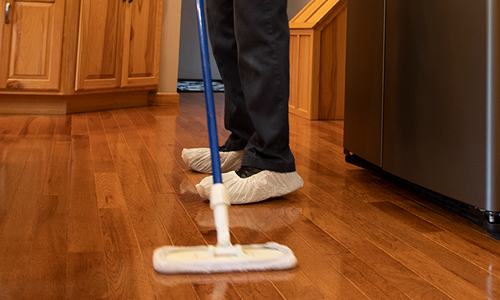 Using mop to clean hardwood flooring in a residential kitchen